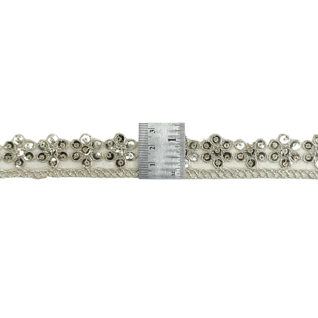 Decorative lace trim with crystals and a ruler for scale on a white background